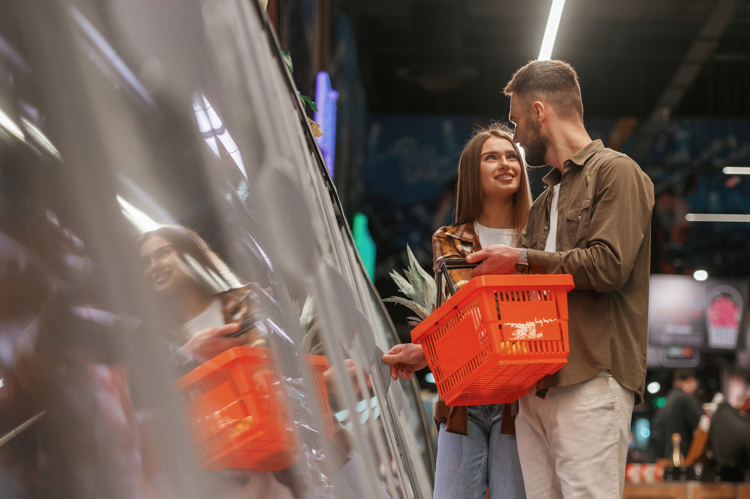 casal carregando uma cesta de mercadoria no supermercado